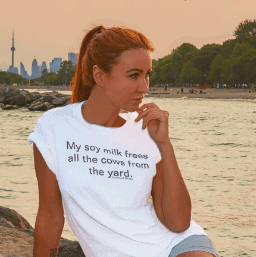A white t-shirt with the humorous and vegan-friendly slogan "My soy milk frees all the cows from the yard." printed on it.