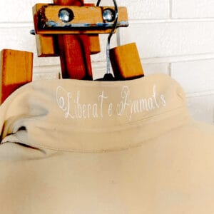 A close-up of a beige shirt with the phrase "Liberate Animals" embroidered on the back.
