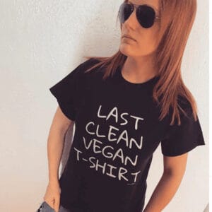 A woman wearing sunglasses and a t-shirt from The Honest Whisper with the message "Last Clean Vegan T-Shirt."