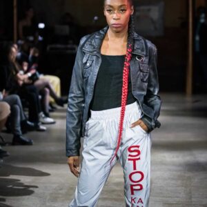 A model walking the runway at The Vegan Fashion Show wearing pants with the message "STOP killing animals" from The Honest Whisper.