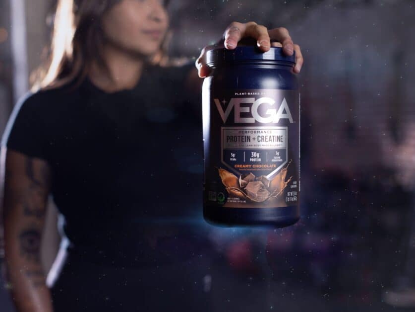 Person holding a tub of Vega Clean and Proven Vegan Performance Powder Protein plus Creatine in Creamy Chocolate flavour.
